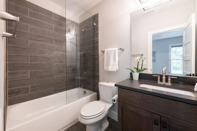 full bathroom featuring vanity, tiled shower / bath combo, and toilet