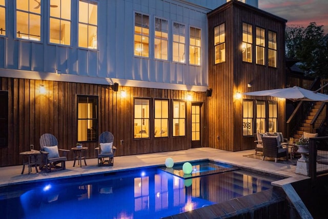 back house at dusk with a patio area and an outdoor living space with a fire pit