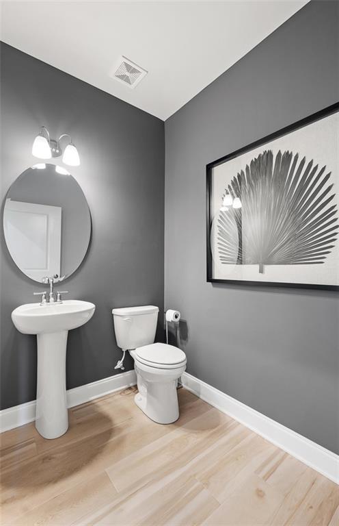 bathroom with toilet and hardwood / wood-style flooring