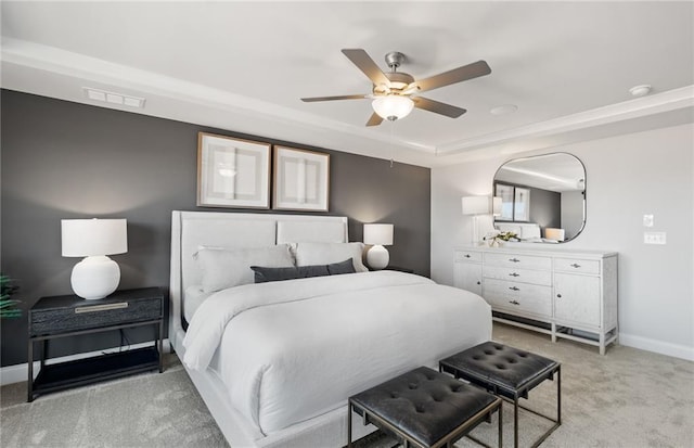 bedroom with ceiling fan, light colored carpet, and a raised ceiling