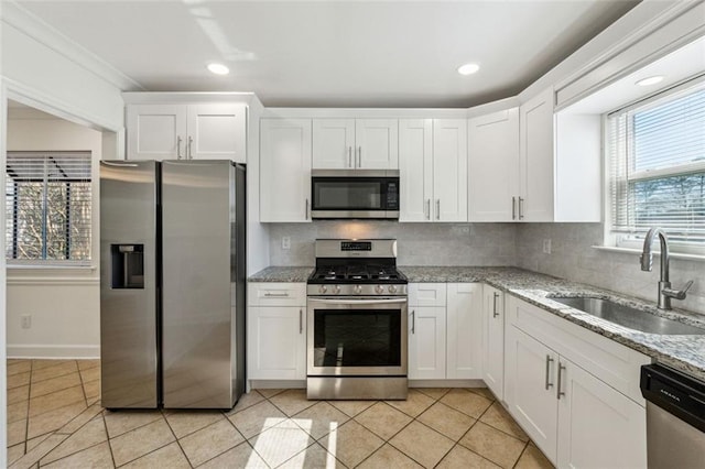 kitchen with tasteful backsplash, sink, white cabinets, light stone counters, and stainless steel appliances