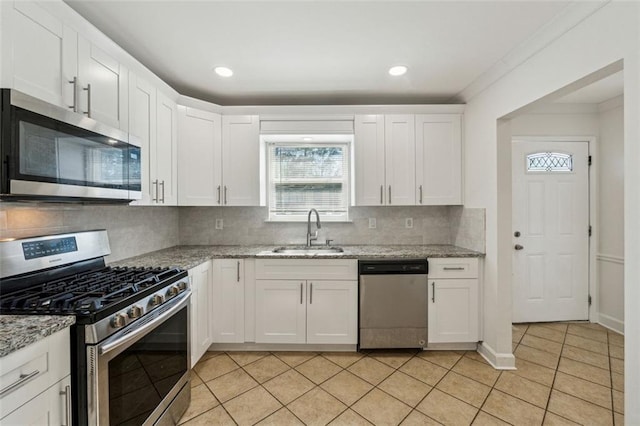 kitchen featuring white cabinetry, sink, light tile patterned floors, light stone counters, and stainless steel appliances