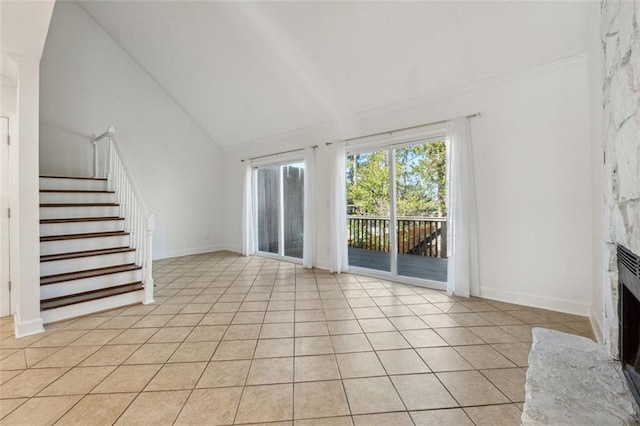 unfurnished living room featuring a premium fireplace, light tile patterned floors, and high vaulted ceiling