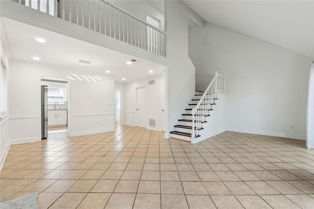 unfurnished living room with light tile patterned flooring, sink, and high vaulted ceiling