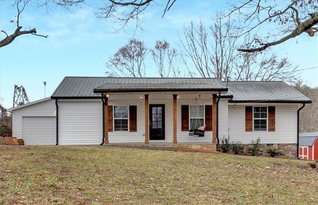 single story home with a garage, covered porch, and a front lawn