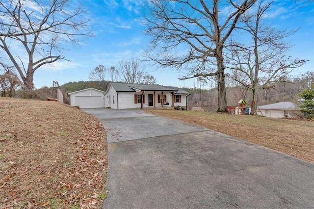 ranch-style home with a porch, a garage, an outdoor structure, and a front lawn