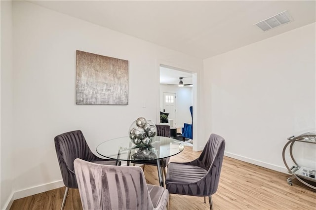 dining space with light wood-type flooring, visible vents, and baseboards
