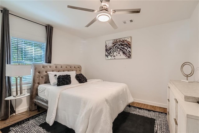 bedroom featuring baseboards, wood finished floors, visible vents, and a ceiling fan