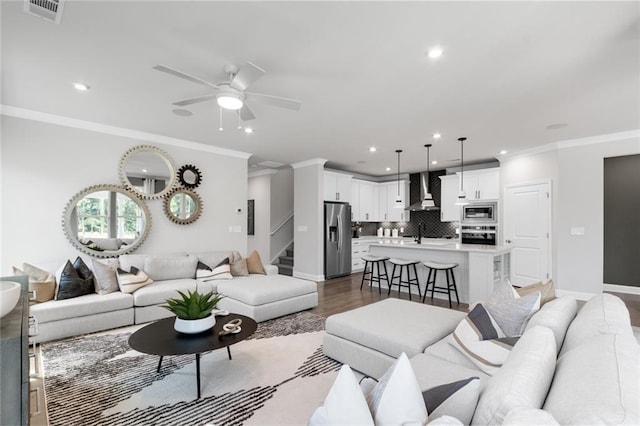 living room with ceiling fan, dark hardwood / wood-style floors, sink, and ornamental molding