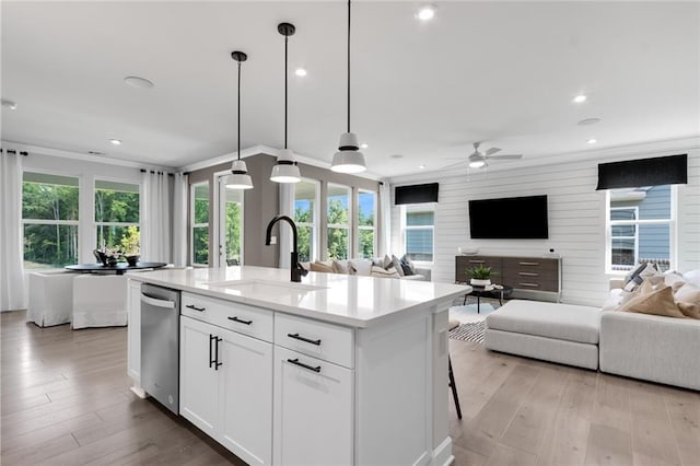 kitchen with white cabinetry, a healthy amount of sunlight, a center island with sink, and sink