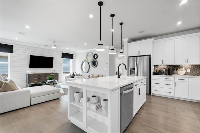 kitchen with white cabinets, decorative light fixtures, and a kitchen island with sink