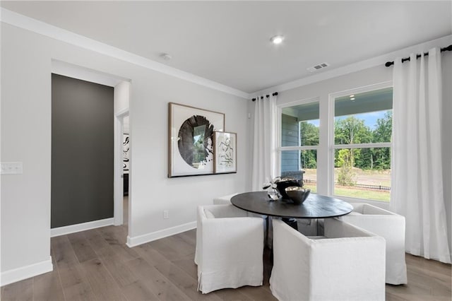 dining room with wood-type flooring and crown molding