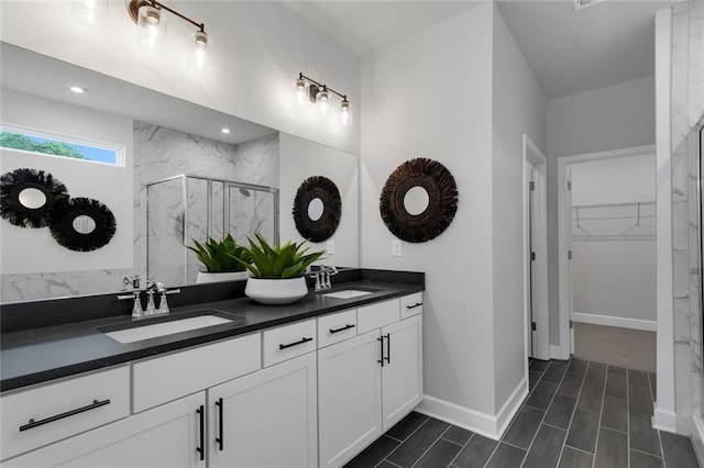 bathroom featuring a shower with door and vanity