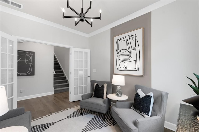 living area with a chandelier, hardwood / wood-style floors, ornamental molding, and french doors