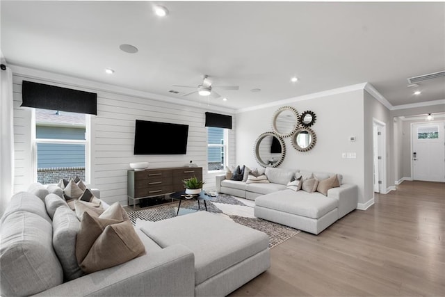 living room with ornamental molding, light wood-type flooring, plenty of natural light, and ceiling fan