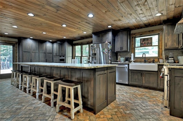 kitchen featuring appliances with stainless steel finishes, a sink, wood ceiling, and decorative backsplash