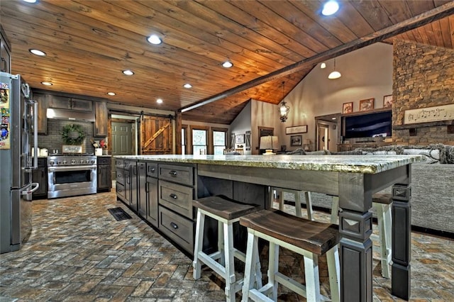 kitchen with a barn door, wood ceiling, appliances with stainless steel finishes, open floor plan, and under cabinet range hood