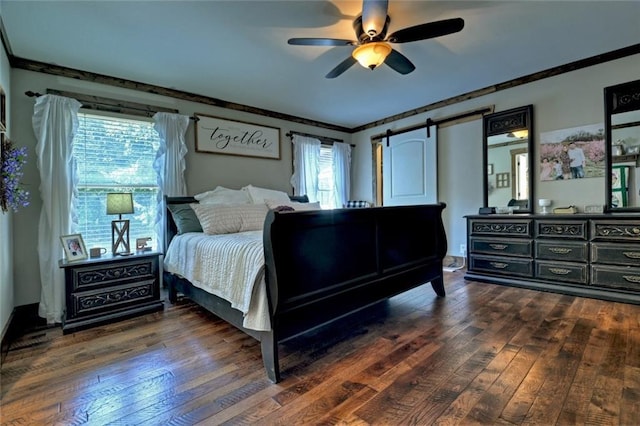 bedroom featuring a barn door, crown molding, and dark wood-type flooring