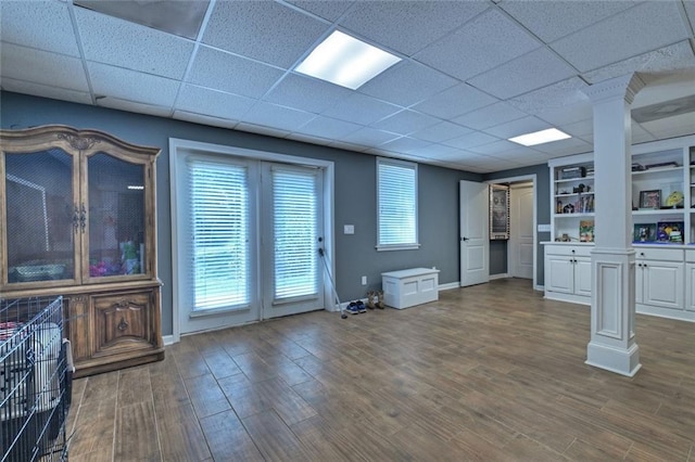 unfurnished living room with baseboards, wood finished floors, and ornate columns