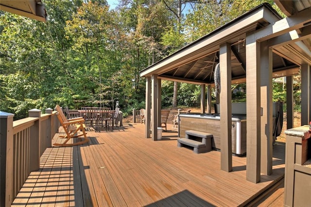 deck with a hot tub, outdoor dining area, and a gazebo