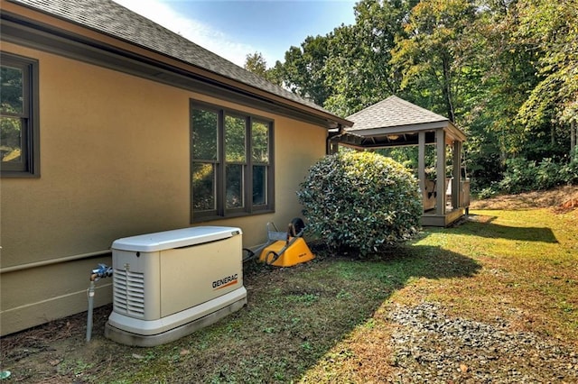 exterior space with a yard, a gazebo, a shingled roof, and stucco siding