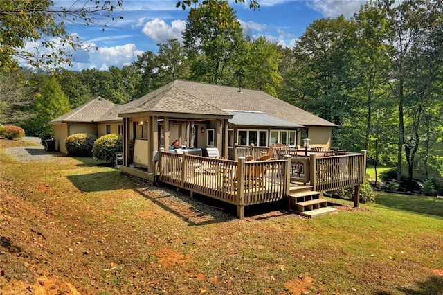 rear view of house featuring a shingled roof, a yard, and a deck