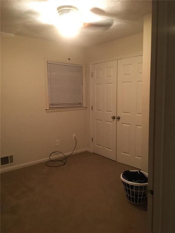 unfurnished bedroom featuring a closet and dark colored carpet