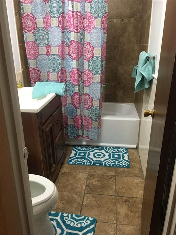 full bathroom with vanity, shower / bath combination with curtain, and toilet