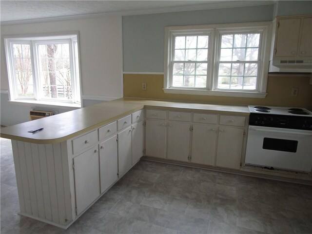 kitchen featuring a wealth of natural light, white electric stove, a peninsula, light countertops, and extractor fan