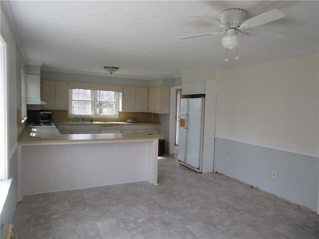 kitchen featuring white appliances, a ceiling fan, a peninsula, light countertops, and cream cabinetry