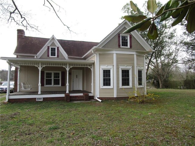 view of front of home with a front yard, a porch, and a chimney