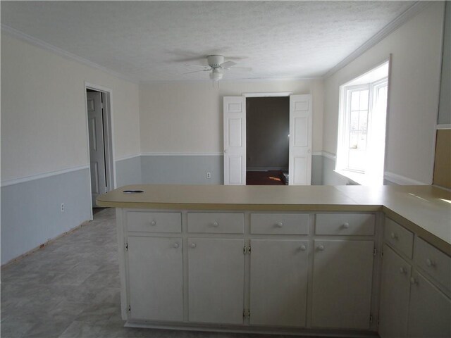 kitchen featuring a peninsula, crown molding, light countertops, and ceiling fan