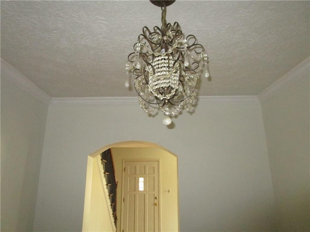 interior details with a textured ceiling, a notable chandelier, arched walkways, and ornamental molding