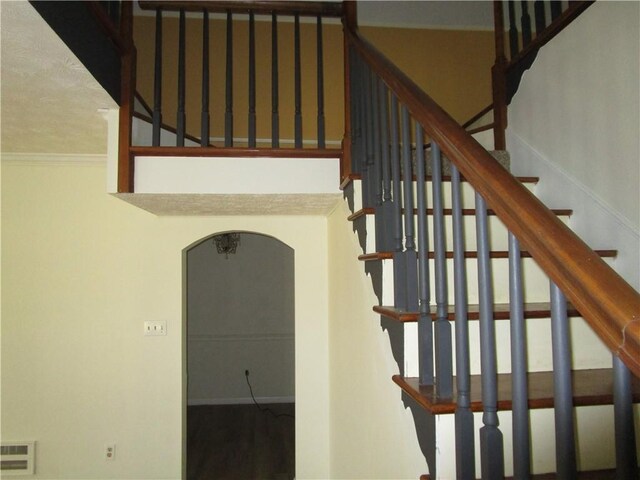 staircase with visible vents, arched walkways, and crown molding