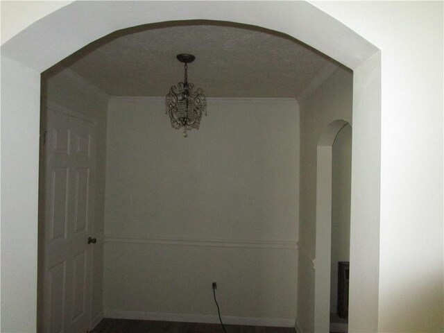 interior space featuring crown molding, a notable chandelier, and arched walkways