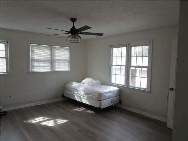 unfurnished bedroom with ceiling fan, baseboards, and wood finished floors