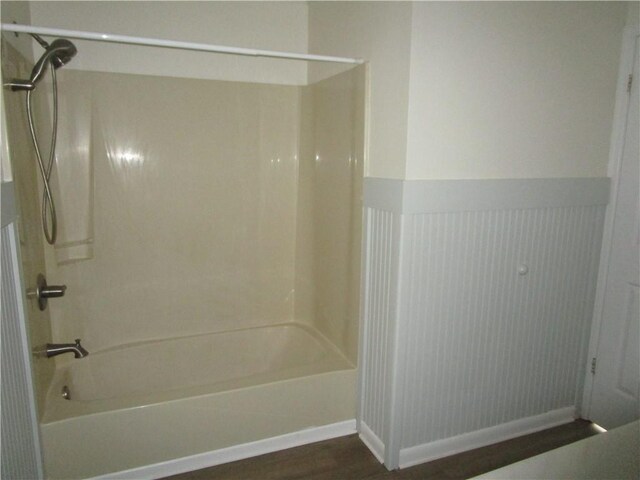 full bathroom featuring wainscoting, bathing tub / shower combination, and wood finished floors