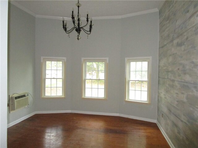 spare room with crown molding, baseboards, a chandelier, a wall unit AC, and wood finished floors