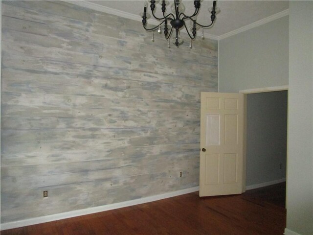 unfurnished dining area featuring a chandelier, wood finished floors, baseboards, and ornamental molding
