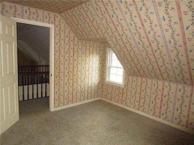 additional living space with wallpapered walls, lofted ceiling, and carpet flooring