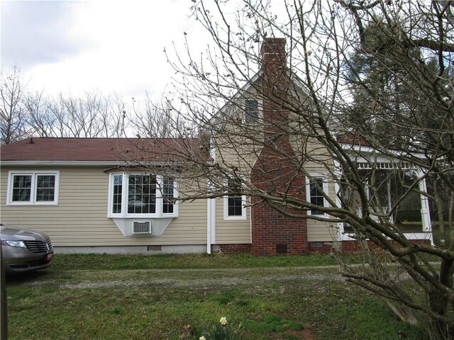 view of home's exterior with crawl space, a lawn, and a chimney