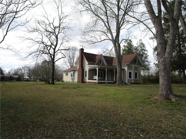 view of front of home with a porch, a chimney, and a front lawn
