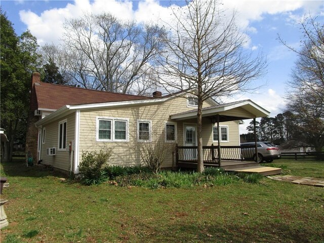 view of front facade featuring a deck, a front lawn, and a chimney