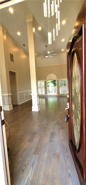 255 Carriage Station Dr, Lawrenceville, GA 30046 - foyer entrance featuring decorative columns, a ceiling fan, a high ceiling, wood finished floors, and wainscoting