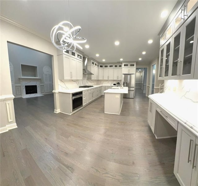 255 Carriage Station Dr, Lawrenceville, GA 30046 - kitchen with stainless steel appliances, wall chimney exhaust hood, a kitchen island, a chandelier, and tasteful backsplash