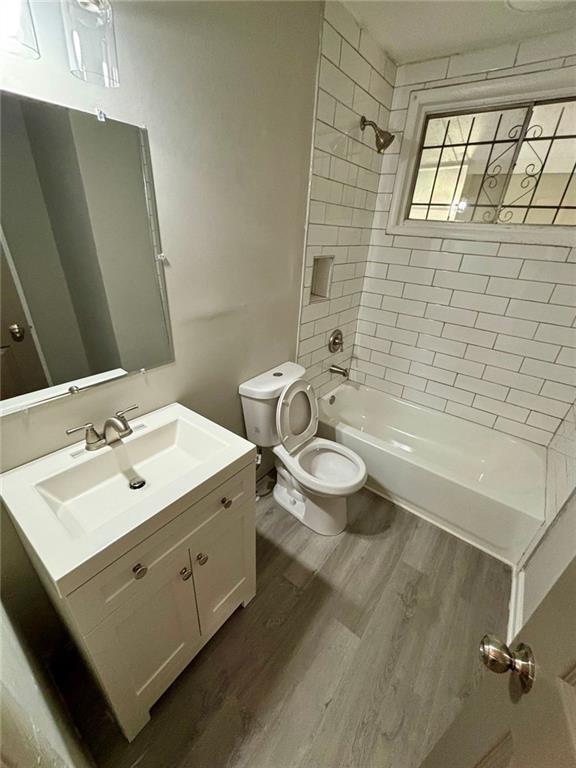 2489 Hillside Dr, Macon, GA 31206 - bathroom featuring wood finished floors, toilet, shower / tub combination, and vanity