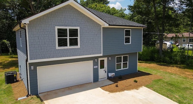view of front facade featuring an attached garage, concrete driveway, a front yard, and central AC unit