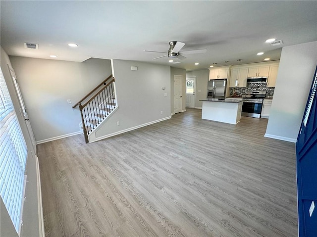 kitchen with visible vents, a ceiling fan, light wood-type flooring, appliances with stainless steel finishes, and open floor plan