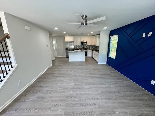 kitchen with wood finished floors, open floor plan, ceiling fan, white cabinetry, and appliances with stainless steel finishes