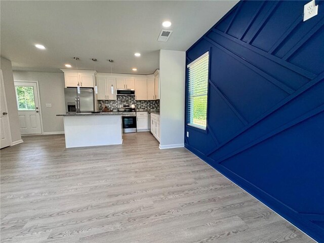 kitchen with tasteful backsplash, light wood-style flooring, white cabinets, appliances with stainless steel finishes, and visible vents